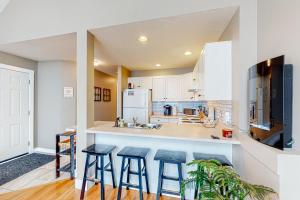 a kitchen with three bar stools and a counter top at Snow Pines & Ice and Cozy in Big White