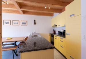 cocina con armarios amarillos y mesa de madera en Racers Retreat 10 en Wengen