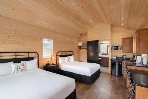 a bedroom with two beds and a kitchen in a cabin at Carmel River Inn in Carmel