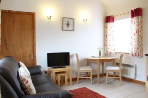 ein Wohnzimmer mit einem Sofa und einem Tisch mit einem TV in der Unterkunft New Inn Lane Holiday Cottages in Evesham