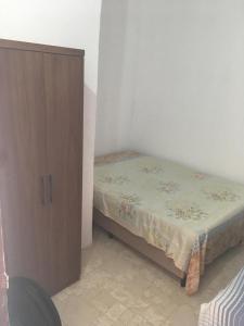 een kleine slaapkamer met een bed en een houten kast bij Casa Temporada Beberibe in Beberibe