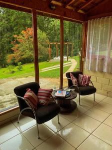 a screened in porch with two chairs and a table at CasaMauá in Visconde De Maua