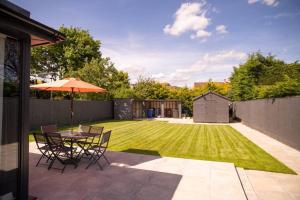 a patio with an umbrella and a table and chairs at Daisy Lodge - Spacious Two Bed Flat - Parking, Netflix, WIFI - Close to Blenheim Palace & Oxford - F1 in Kidlington