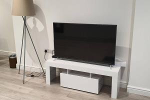 a flat screen tv sitting on top of a white table at Daisy Lodge - Spacious Two Bed Flat - Parking, Netflix, WIFI - Close to Blenheim Palace & Oxford - F1 in Kidlington