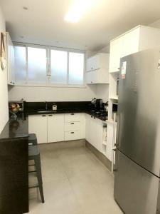 cocina con armarios blancos y nevera de acero inoxidable en Apartamento em copacabana, en Río de Janeiro