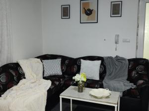 uma sala de estar com um sofá preto e uma mesa em Apartman Raj em Vrnjačka Banja