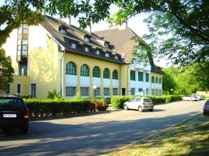 a large yellow building with cars parked in front of it at Hotel Familia in Zamárdi