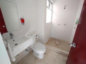 a white bathroom with a toilet and a sink at Hotel Villa Esmeralda in Cuautla Morelos