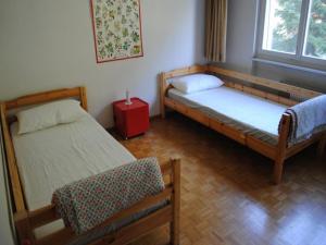 pokój z 2 łóżkami i czerwonym stołem w obiekcie Residence Eden Roc w mieście Crans-Montana
