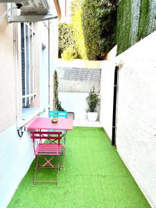 einen rosa Tisch und Stühle auf einer Terrasse mit grünem Gras in der Unterkunft Luxury Dreams Balneo in Le Cannet