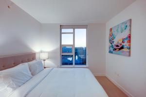 a white bedroom with a large bed and a window at Downtown Properties in Vancouver