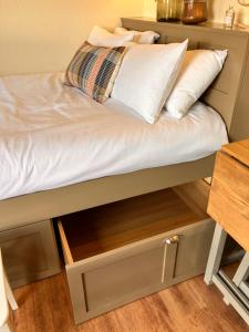 a bed with a pull out drawer and white pillows at Ballydorn Stay in Killinchy
