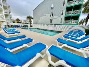 a group of blue and white lounge chairs next to a swimming pool at Lovely 2 bedroom condo with ocean view 304 in Myrtle Beach