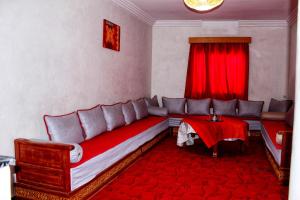 een woonkamer met een bank en een rode tafel bij Appartement Afgo Ouarzazate in Ouarzazate