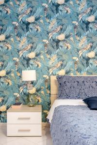 una camera da letto con carta da parati floreale blu e letto di Green Apartment Catania a Catania