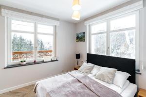 a bedroom with a bed and two windows at Apartamenty Panorama Szczawnica in Szczawnica