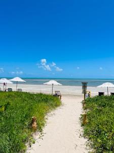 a sandy beach with umbrellas and chairs and the ocean at Pousada San Giovanni in Japaratinga