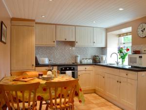 a kitchen with a table with chairs and a counter top at Gullieside Cottage in Borgue