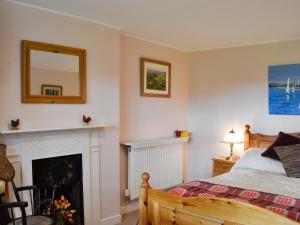a bedroom with a bed and a fireplace at Gullieside Cottage in Borgue