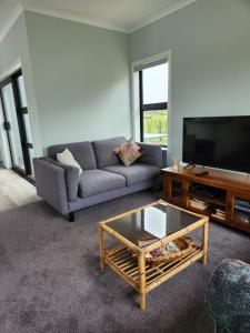 sala de estar con sofá y mesa de centro en Aberdeen Cottage with Hobbit House sleep-out, en Tamahere