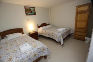 una habitación de hotel con 2 camas y una puerta en Witobi Hostal, en Cajamarca