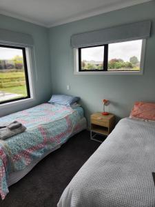 2 camas en una habitación con 2 ventanas en Aberdeen Cottage with Hobbit House sleep-out, en Tamahere