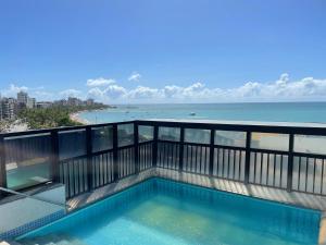 a swimming pool on a balcony with the ocean in the background at Ótimo Ap na Pajuçara - Maceió in Maceió