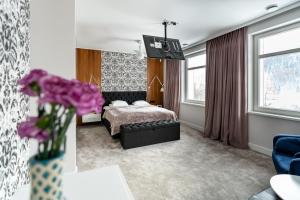 Apartamenty Panorama Szczawnica في شتافنيتسه: غرفة نوم مع سرير و مزهرية من الزهور الأرجوانية