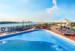 盧克索的住宿－Nile Cruise 3 & 4 & 7 Nights included abo Simbel tour，水边带椅子和遮阳伞的游泳池