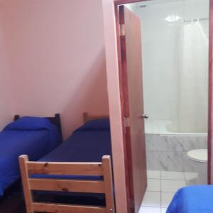 a bedroom with two beds and a bathroom with a shower at Hostería Residencial Santa Rosa in Los Andes