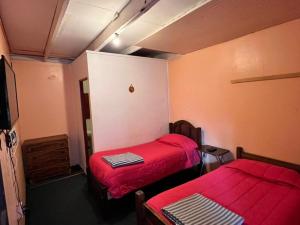 two beds in a small room with red sheets at Hostería Residencial Santa Rosa in Los Andes