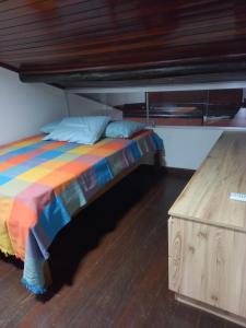 Una cama con una manta colorida y una mesa de madera. en Flat 218 - Duplex no Condomínio Winterville em Gravatá, en Gravatá