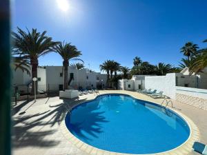 a large swimming pool with chairs and palm trees at Casita Marta Fuerteventura in Costa Calma