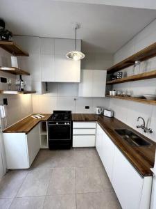 cocina con armarios blancos y estufa negra en Casa R43 en Godoy Cruz