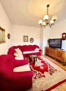 a living room with a red couch and a tv at Ovcina Garden view residence in Sarajevo