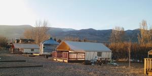 a group of buildings and a barn with mountains in the background at Cozy Glamp Tents at Wildland Gardens in Joseph