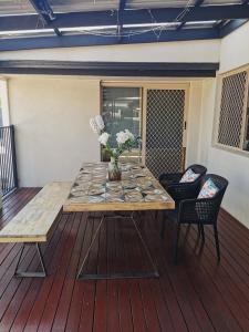 una mesa de madera y sillas en una terraza en Eight Mile Plains House en Brisbane