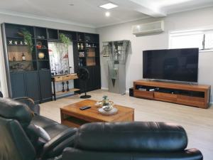 uma sala de estar com uma televisão, um sofá e uma mesa em Eight Mile Plains House em Brisbane