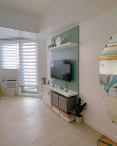 a living room with a tv and a mirror at GBU's Studio with Balcony at Azure North Pampanga in San Fernando