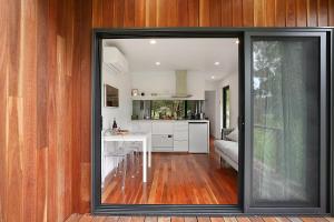 een keuken met een grote glazen deur naar een woonkamer bij Timboon Tiny Homes in Timboon