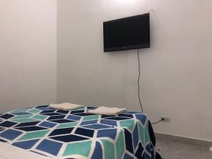 1 dormitorio con 1 cama y TV en la pared en Apartamento cómodo , céntrico y bien ubicado Apto 402, en Medellín