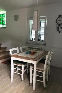 einen weißen Esstisch mit weißen Stühlen und einer Uhr in der Unterkunft Holiday house with a parking space Fuzine, Gorski kotar - 20330 in Fužine + 7 Fotos