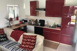eine Küche mit roten Schränken und einem Sofa in einem Zimmer in der Unterkunft Holiday house with a parking space Fuzine, Gorski kotar - 20332 in Fužine