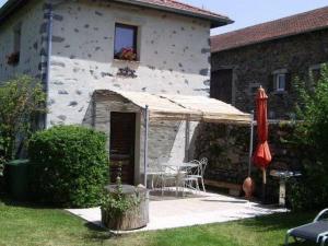 a patio with a table and an umbrella in front of a house at Ancien pigeonnier restauré avec terrasse, terrain clos et équipements bébé à Sarlanges, Retournac - FR-1-582-167 in Retournac