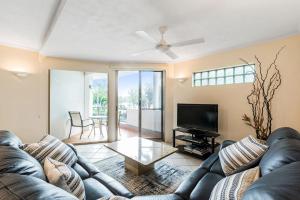 Una sala de estar con un sofá de cuero y un televisor. en 7 Como Noosa, en Noosaville