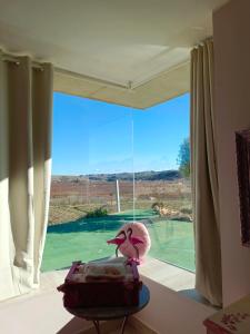 um quarto com uma grande janela com um pássaro cor-de-rosa numa mesa em Cabezo Buñuel Hostal em Calanda