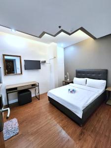 Dormitorio con cama, escritorio y TV en New Kong's Hotel en Olongapo