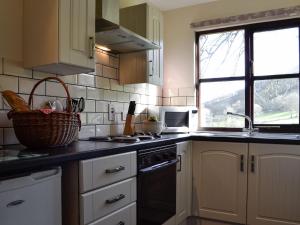 uma cozinha com um lavatório e um fogão forno superior em Robins Retreat - Uk6548 em Llanfihangel-Bryn-Pabuan