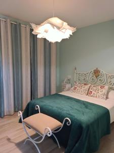 a bedroom with a green bed with a chair and a chandelier at Cabezo Buñuel alojamiento Rural in Calanda +208 photos