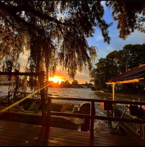 un bateau sur l'eau avec le coucher du soleil en arrière-plan dans l'établissement Cabañas Burdeos, à Tigre